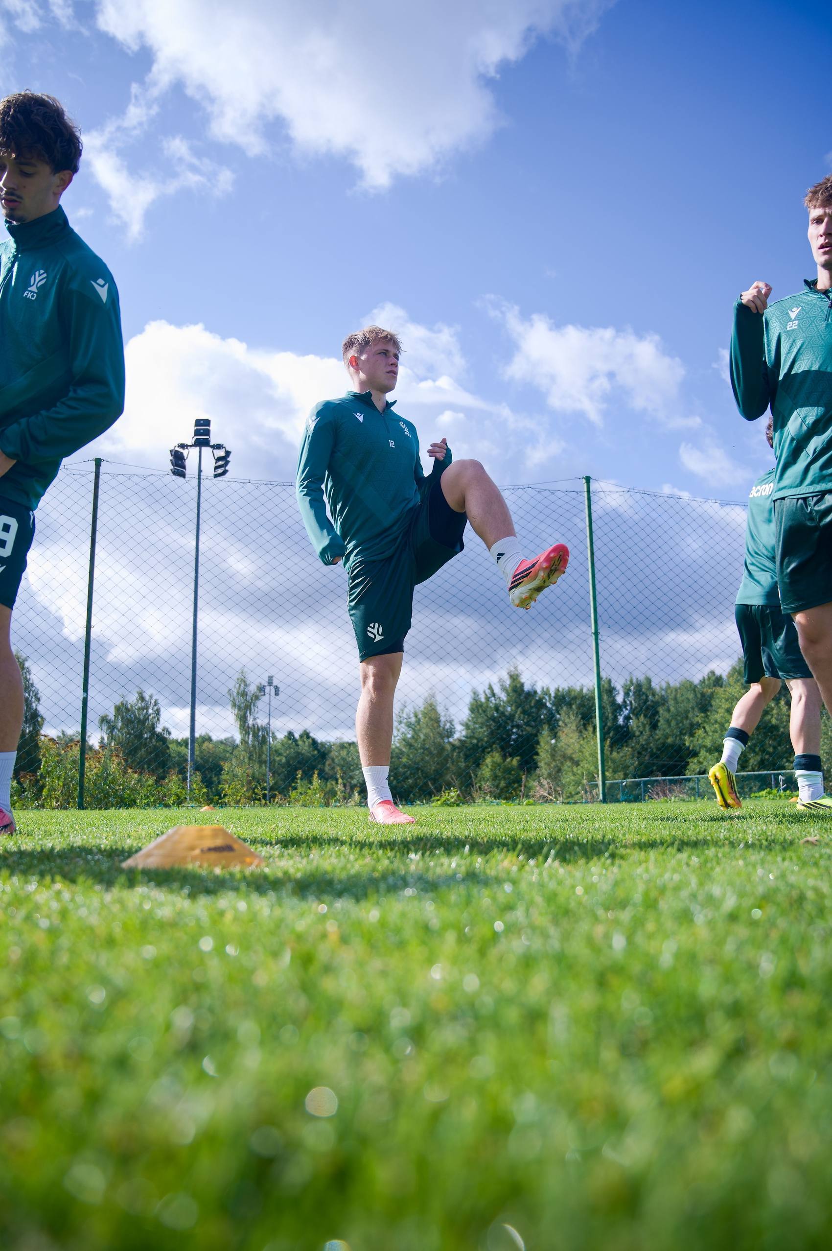 Fotbalisté při rozcvičce proti modré obloze