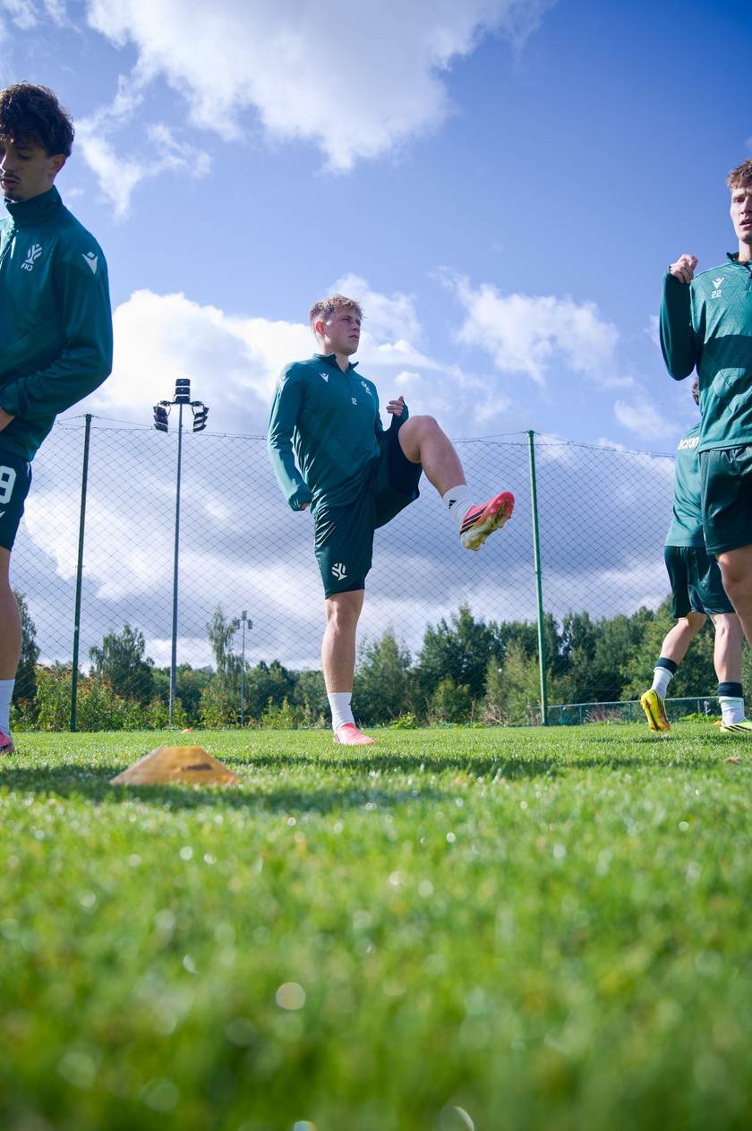 Fotbalisté při rozcvičce proti modré obloze