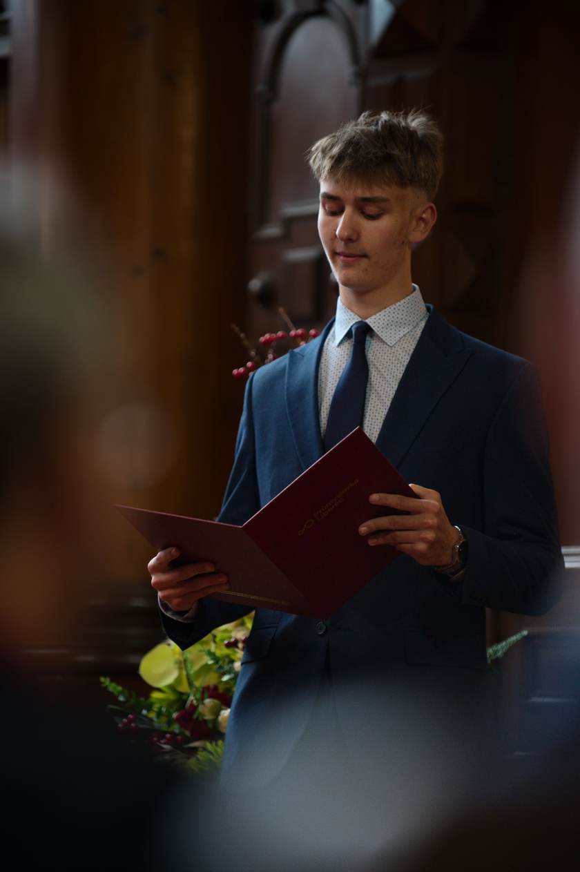 Maturant v obleku čte slavnostní projev z desek