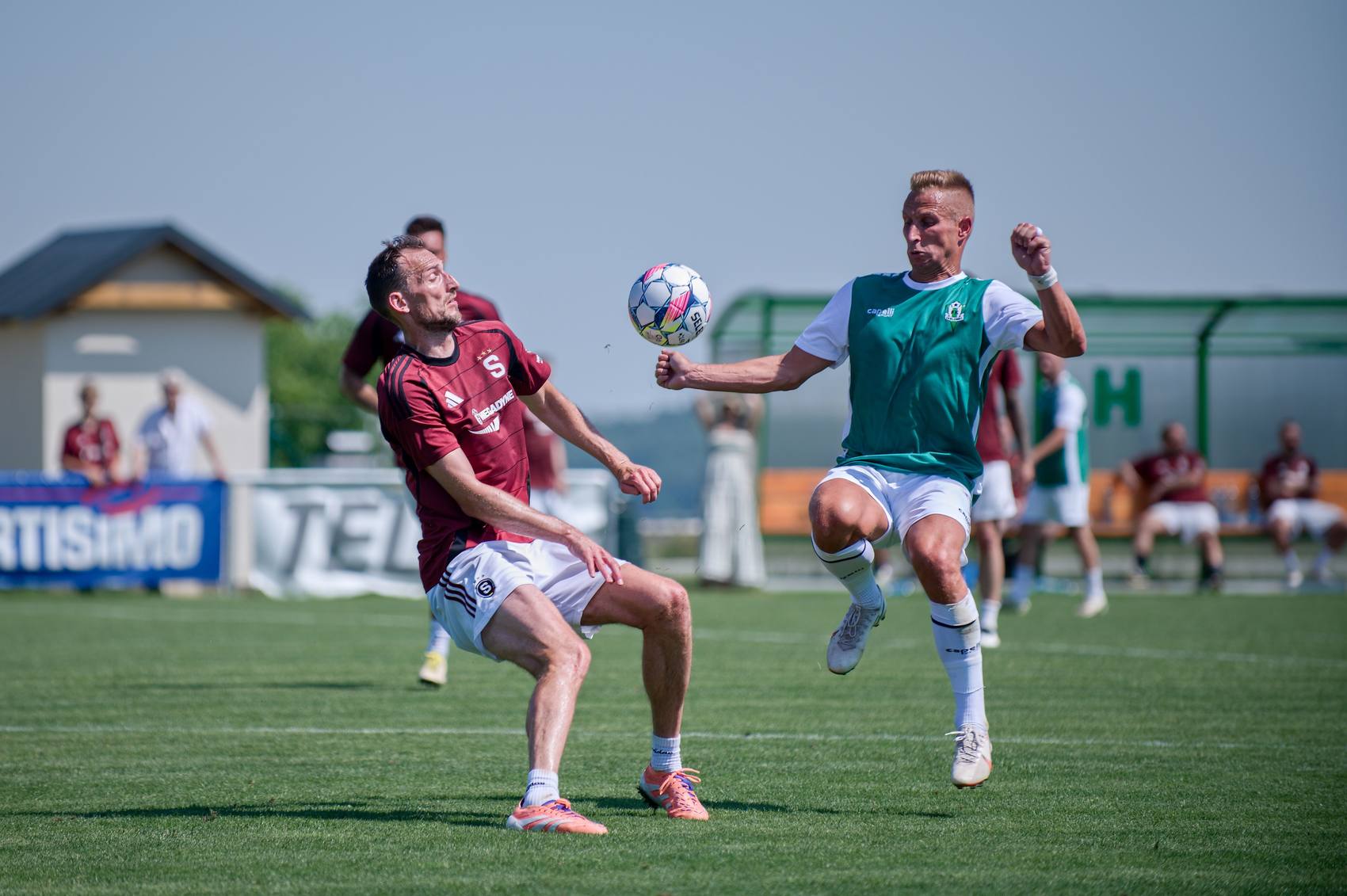 Dva fotbalisté ve výskoku bojují o vysoký míč