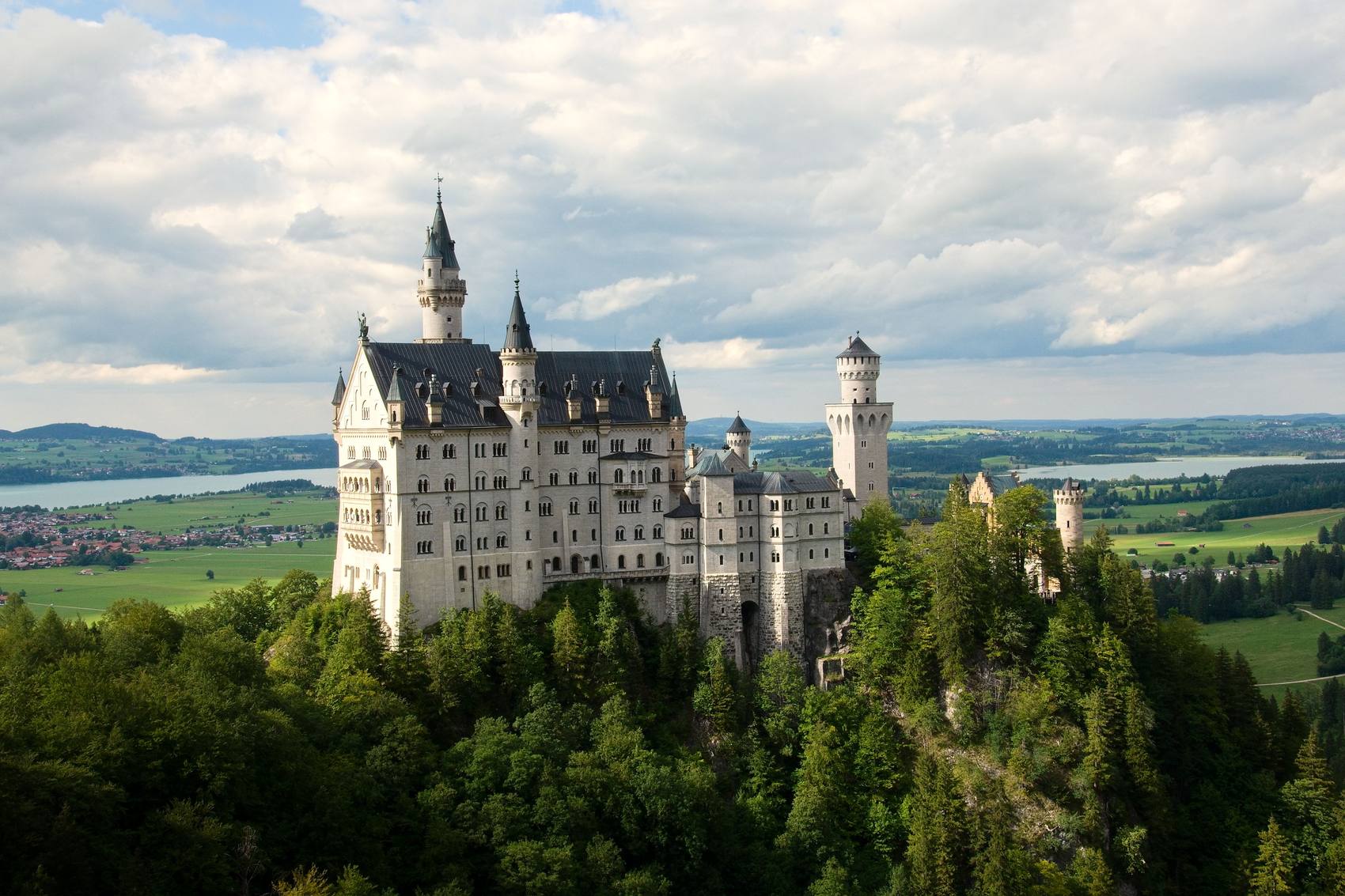 Zámek Neuschwanstein na zalesněném ostrohu nad krajinou